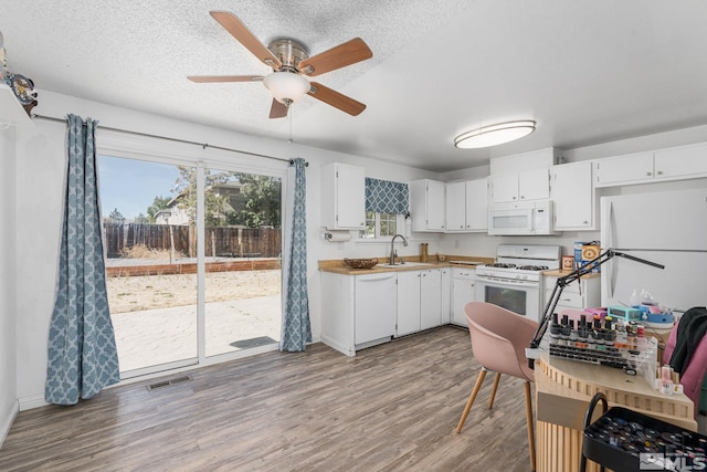 kitchen featuring white cabinets, hardwood / wood-style floors, sink, and white appliances