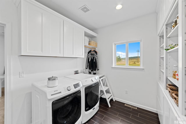 laundry area with separate washer and dryer, dark hardwood / wood-style floors, and cabinets