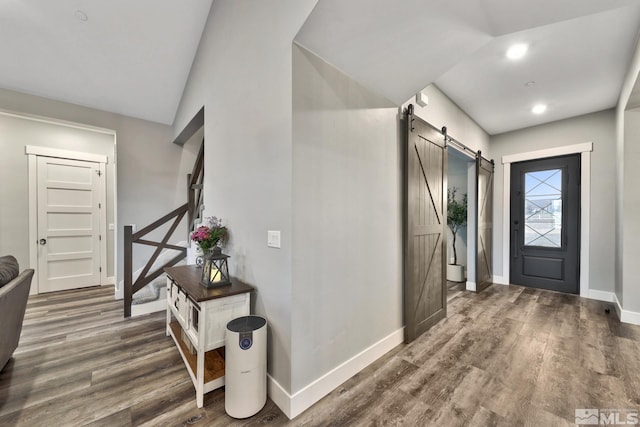 foyer featuring lofted ceiling, a barn door, and dark hardwood / wood-style flooring