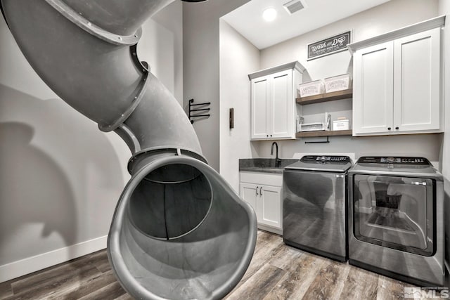 washroom with cabinets, dark hardwood / wood-style floors, washer and dryer, and sink