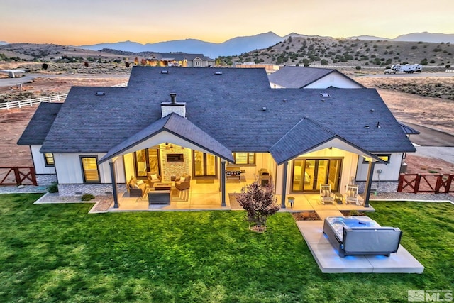 back house at dusk with an outdoor living space, a yard, a patio area, and a mountain view