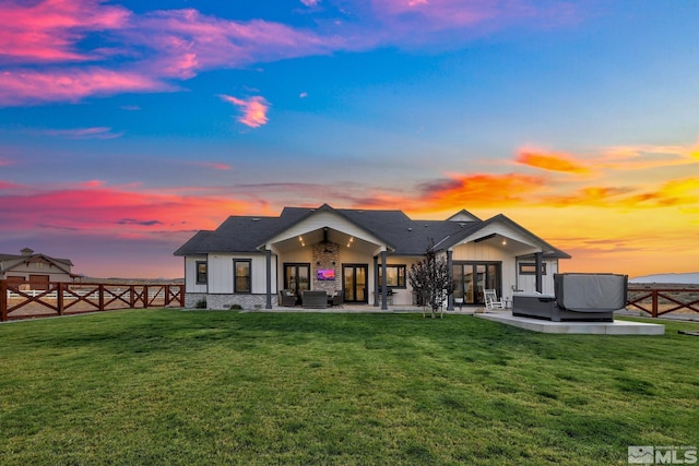 back house at dusk with an outdoor hangout area, a patio, and a lawn