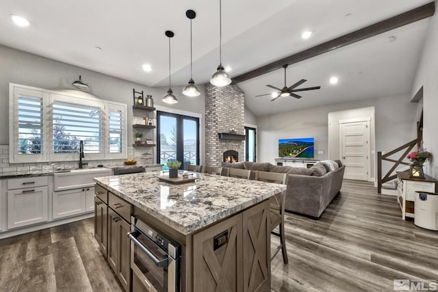 kitchen with white cabinets, light stone countertops, a fireplace, and a center island