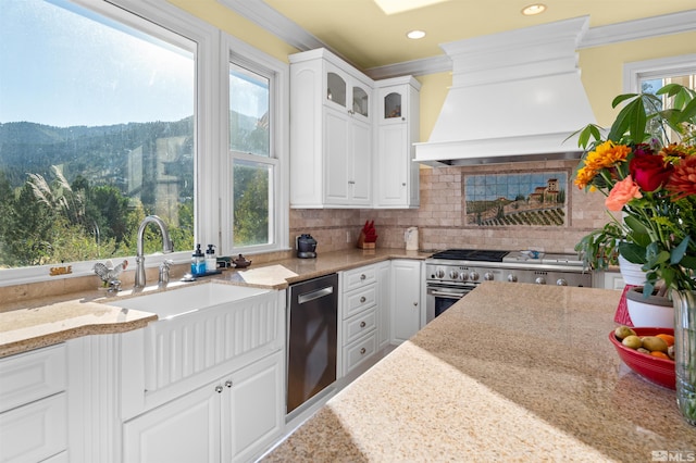 kitchen featuring light stone counters, white cabinets, appliances with stainless steel finishes, and a wealth of natural light