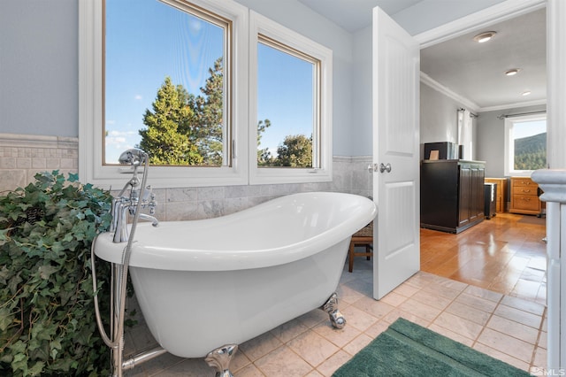 bathroom with ornamental molding, a tub to relax in, a healthy amount of sunlight, and vanity