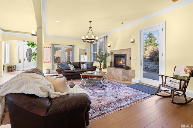 living room featuring ornamental molding, a tile fireplace, hardwood / wood-style floors, and a chandelier