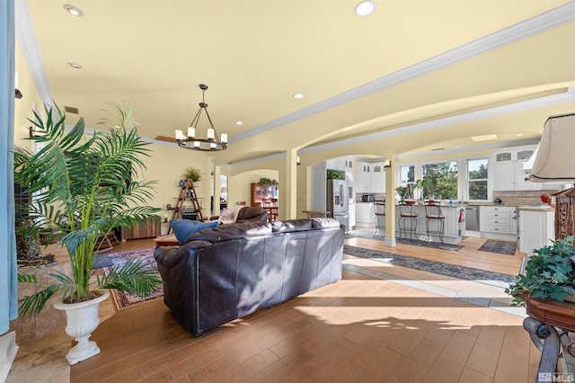 living room featuring a notable chandelier, light wood-type flooring, and ornamental molding