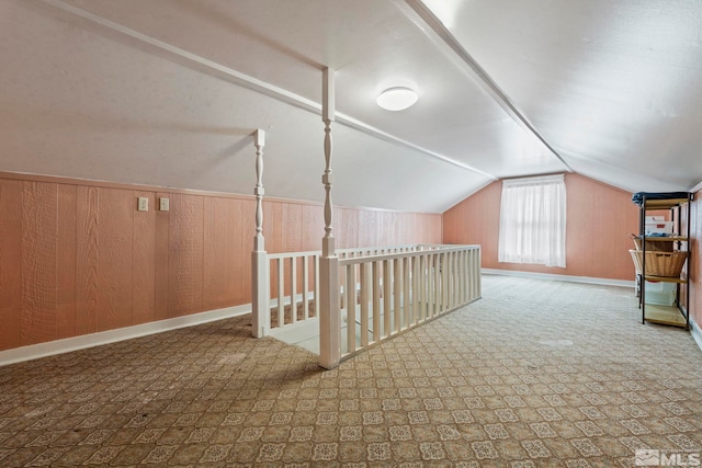 additional living space featuring wooden walls and lofted ceiling