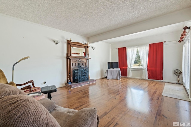 living room with a fireplace, wood-type flooring, crown molding, and a textured ceiling