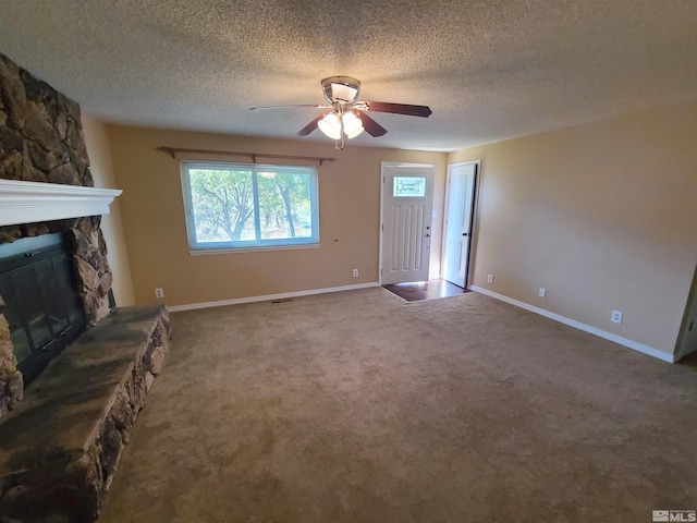 unfurnished living room with ceiling fan, a textured ceiling, a fireplace, and carpet flooring