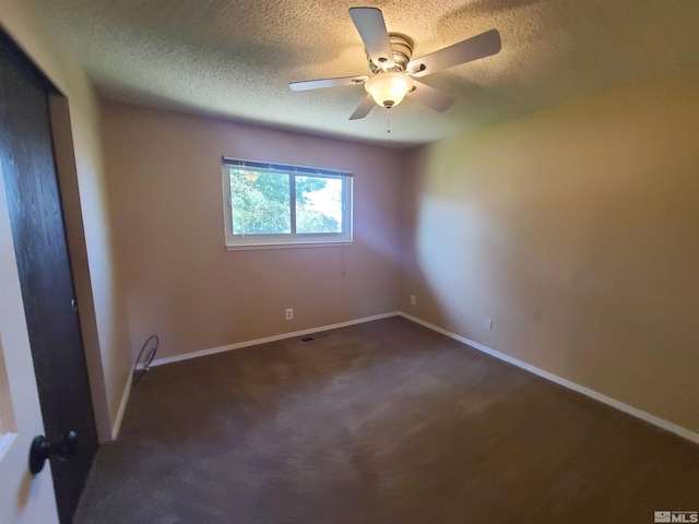 unfurnished room featuring ceiling fan, dark carpet, and a textured ceiling