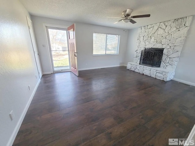 unfurnished living room with a textured ceiling, a fireplace, dark hardwood / wood-style flooring, and a healthy amount of sunlight