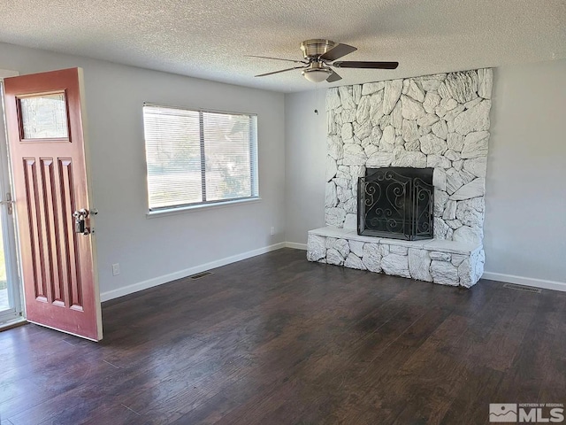 unfurnished living room featuring a healthy amount of sunlight, dark hardwood / wood-style flooring, and a textured ceiling