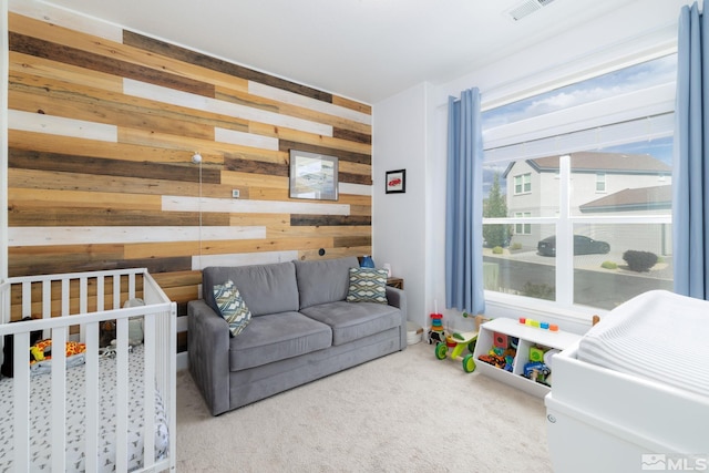 carpeted bedroom with a crib and wood walls