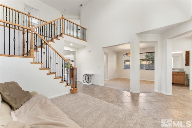 foyer entrance with a towering ceiling and light colored carpet