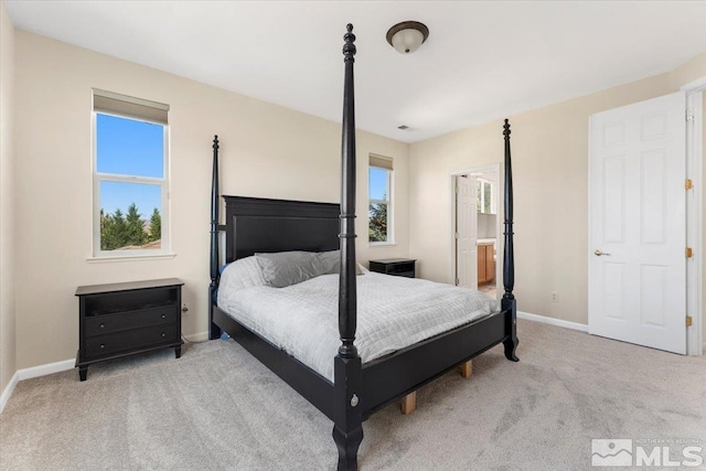 carpeted bedroom featuring connected bathroom and multiple windows