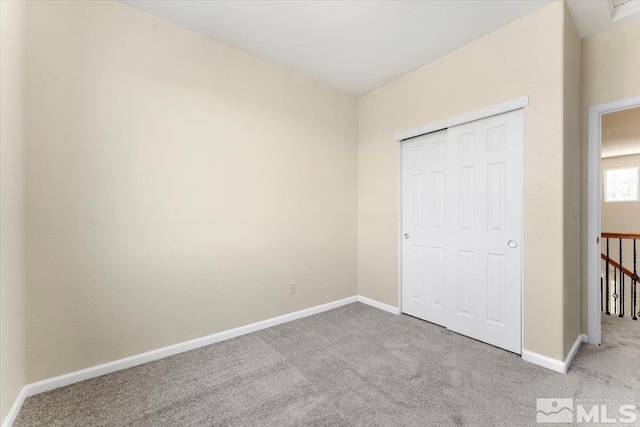 unfurnished bedroom with light carpet and a closet