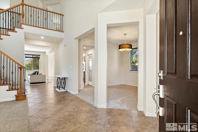 carpeted foyer entrance featuring a towering ceiling