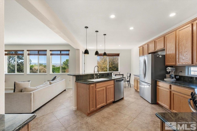 kitchen with sink, appliances with stainless steel finishes, decorative light fixtures, a center island with sink, and light tile patterned floors