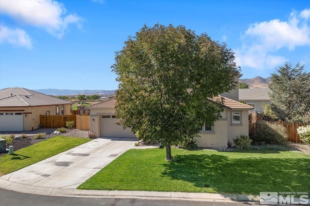 view of front of house with a garage, a front lawn, and a mountain view