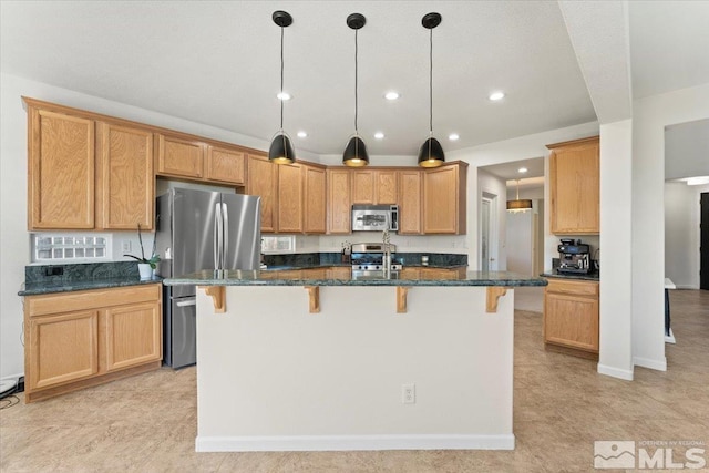 kitchen featuring an island with sink, dark stone counters, appliances with stainless steel finishes, and a kitchen breakfast bar