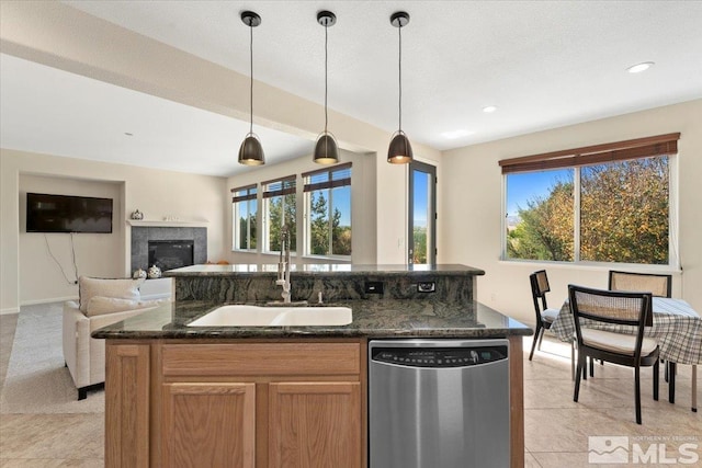 kitchen with pendant lighting, dark stone countertops, sink, and stainless steel dishwasher