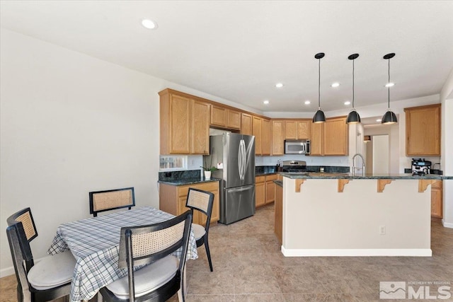 kitchen featuring a center island, stainless steel appliances, dark stone countertops, decorative light fixtures, and light tile patterned floors