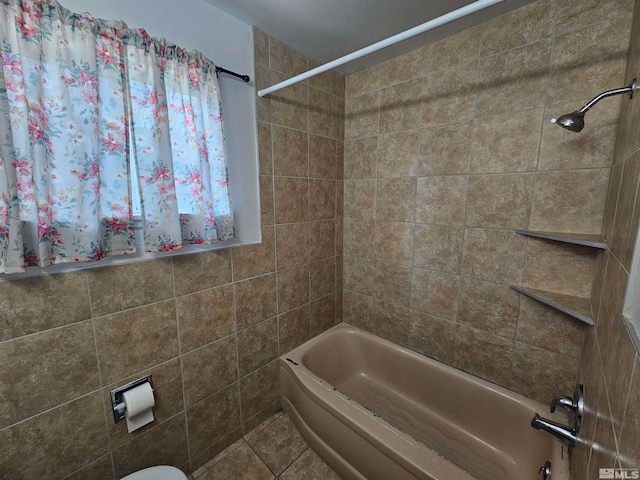 bathroom featuring tile patterned floors, toilet, and tiled shower / bath combo