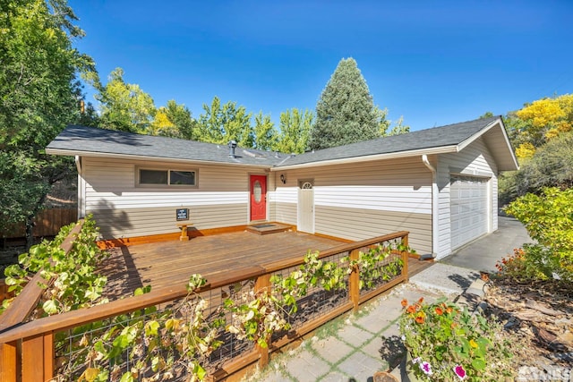 rear view of house with a garage, an outdoor structure, and a deck