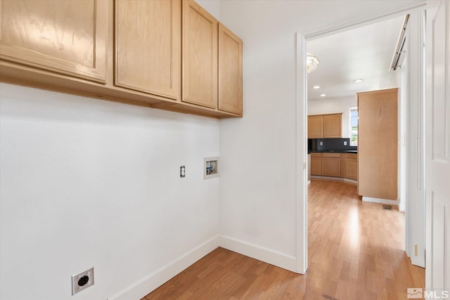 laundry room with hookup for a washing machine, cabinets, light hardwood / wood-style flooring, and electric dryer hookup