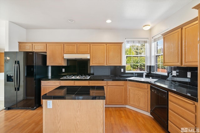 kitchen featuring sink, black appliances, a center island, light wood-type flooring, and decorative backsplash