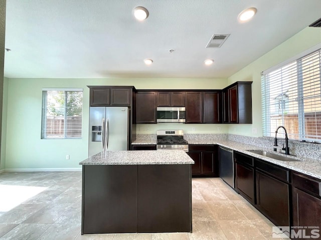 kitchen with a wealth of natural light, appliances with stainless steel finishes, sink, and a center island