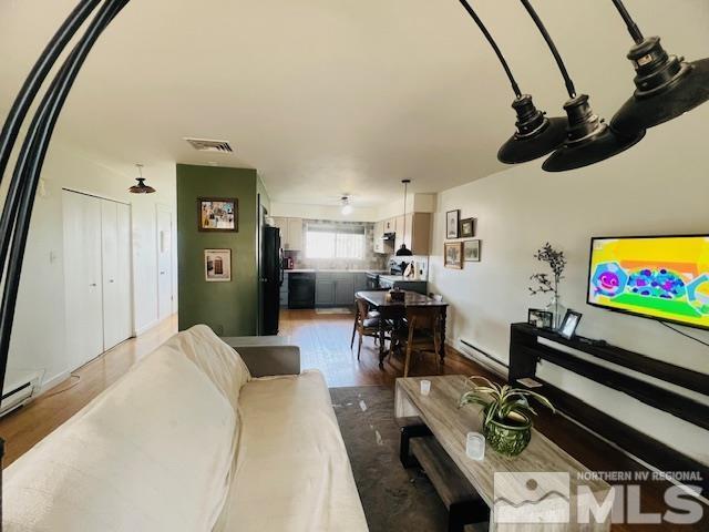 living room with a baseboard heating unit, wood finished floors, and visible vents