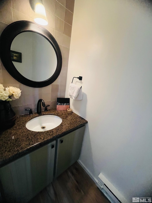 bathroom with baseboards, wood finished floors, vanity, and decorative backsplash