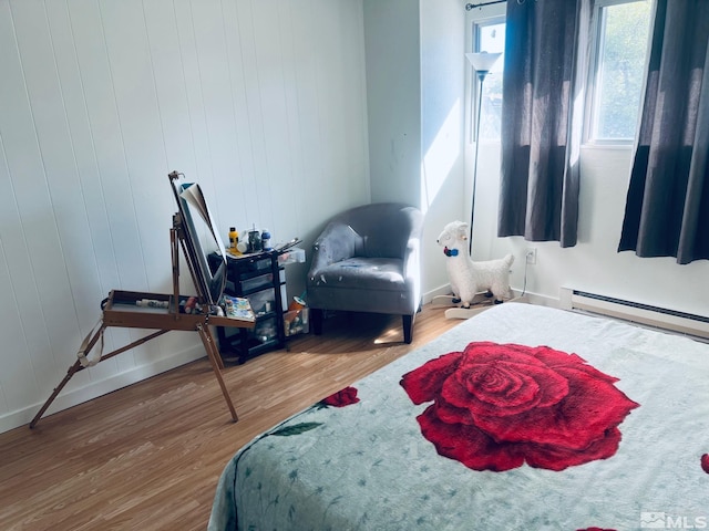 bedroom with a baseboard radiator, baseboards, and wood finished floors