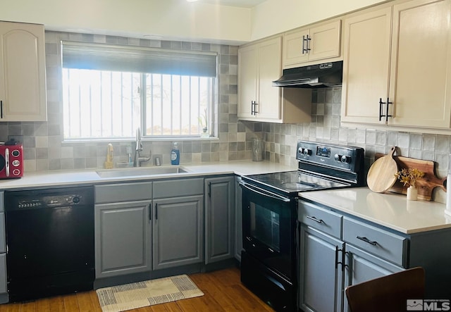 kitchen featuring under cabinet range hood, light countertops, gray cabinets, a sink, and black appliances