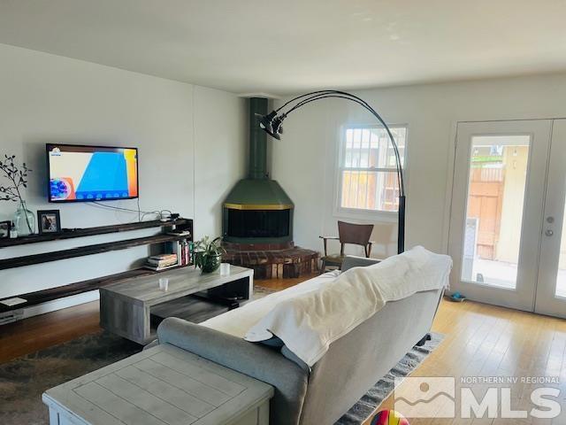 living area featuring light wood-style floors, a wood stove, and french doors