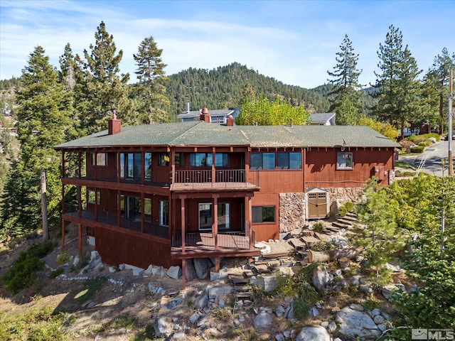 back of property featuring a mountain view and a balcony