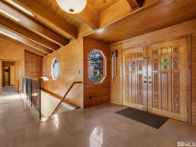 tiled entryway with wood ceiling, vaulted ceiling with beams, and wooden walls