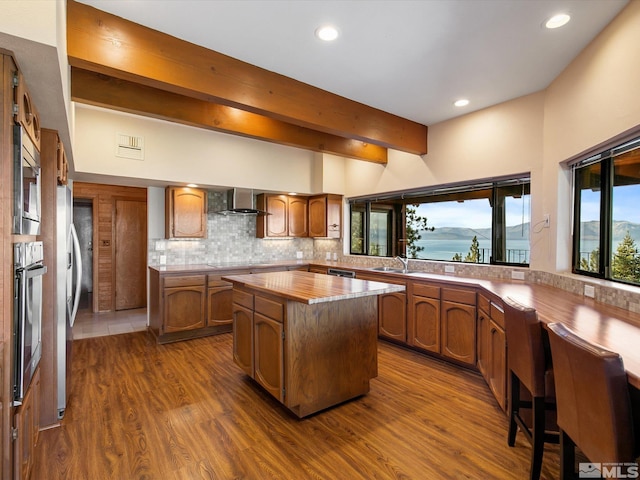 kitchen featuring beam ceiling, tasteful backsplash, a kitchen island, dark wood-type flooring, and stainless steel appliances