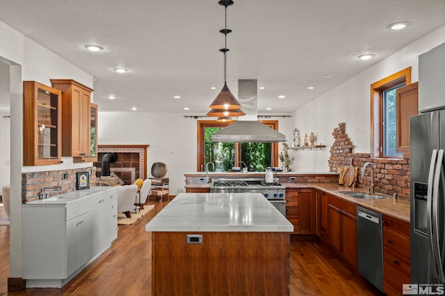 kitchen featuring island exhaust hood, a kitchen island, decorative light fixtures, sink, and appliances with stainless steel finishes