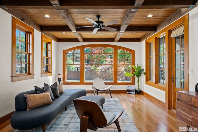 sitting room featuring light hardwood / wood-style floors, wood ceiling, beamed ceiling, and ceiling fan