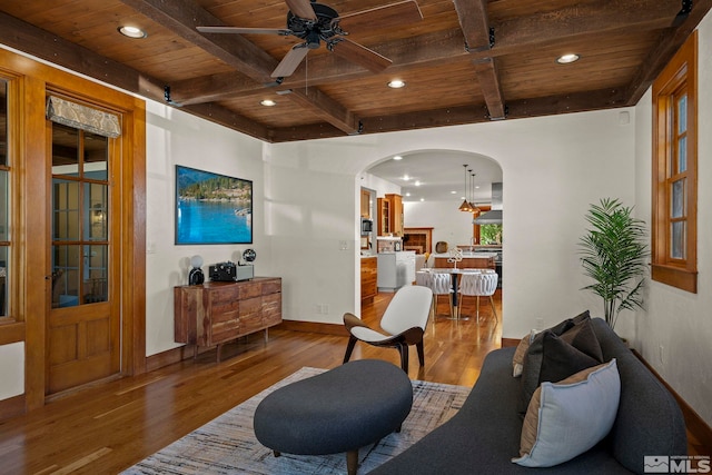 living room featuring ceiling fan, hardwood / wood-style flooring, beam ceiling, and wooden ceiling