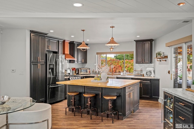 kitchen with decorative backsplash, pendant lighting, appliances with stainless steel finishes, and a center island