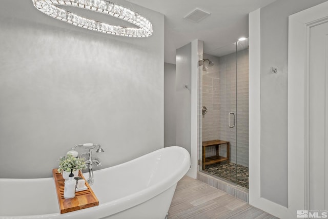 bathroom with separate shower and tub and a notable chandelier