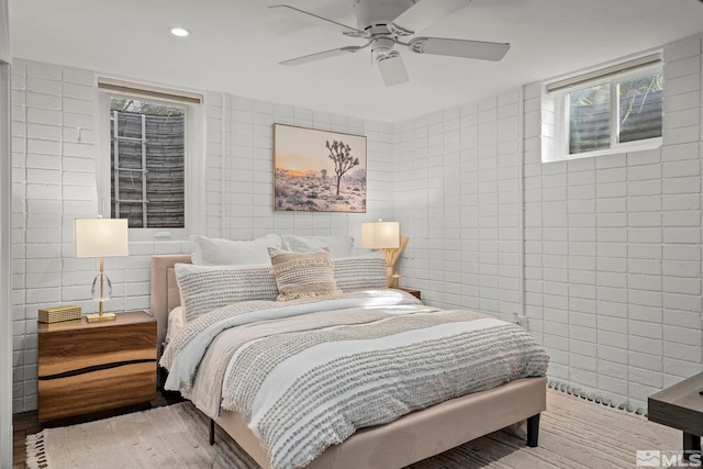 bedroom featuring ceiling fan, tile walls, and wood-type flooring