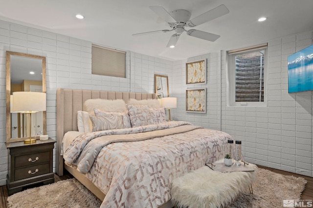 bedroom featuring wood-type flooring, tile walls, and ceiling fan