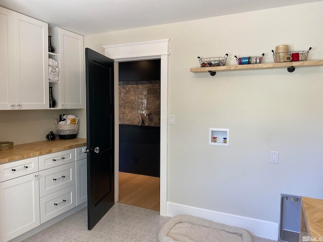 washroom featuring washer hookup, cabinets, and light tile patterned flooring