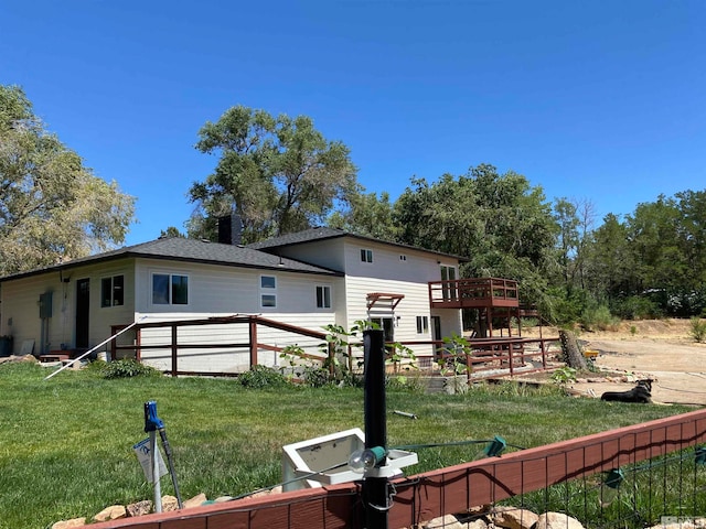 rear view of house featuring a deck and a lawn