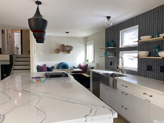 kitchen with pendant lighting, sink, stainless steel dishwasher, and white cabinetry